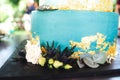 Closeup of base tier of wedding cake. Various flowers at blue round cake. Wedding day concept.