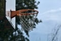 Closeup of a basketball hoop with trees and a cloudy sky as background Royalty Free Stock Photo