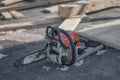 Closeup of a battery-powered chainsaw and an adze tool at the construction site