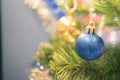 Closeup bauble hanging from a decorated Christmas tree on blurred background