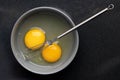 Closeup of beaten eggs in a bowl with a whisk on a black table