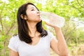 Beautiful Asian woman drinking fresh water in bottle outdoors with nature background Royalty Free Stock Photo