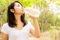 Beautiful Asian woman drinking fresh water in bottle outdoors with nature background Royalty Free Stock Photo