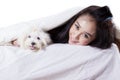 Woman smiling and lying in the bed with her dog Royalty Free Stock Photo