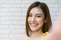 Closeup of beautiful Asian woman wearing off shoulder yellow knitted clothes smilling with white teeth and taking selfie of by Royalty Free Stock Photo