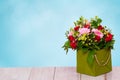 Closeup of a beautiful bouquet with colorful flowers in a decorative green gift box on a bright wooden table over abstract spring Royalty Free Stock Photo