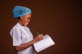 Closeup of a beautiful doctor smiling and taking notes on a brown background Royalty Free Stock Photo