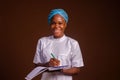 Closeup of a beautiful doctor smiling and taking notes on a brown background Royalty Free Stock Photo