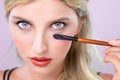 Closeup beautiful girl with flawless applying alluring eye shadow makeup. Royalty Free Stock Photo