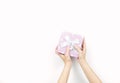 Closeup beautiful and healthy woman hands with neat manicure are holding pink gift box with polka dotted pattern