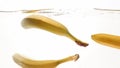 Closeup beautiful image of bananas falling in clear water against white background, Lots of air flaoting air bubbles and Royalty Free Stock Photo