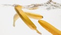 Closeup beautiful image of bananas falling in clear water against white background, Lots of air flaoting air bubbles and Royalty Free Stock Photo