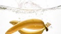 Closeup beautiful image of bananas falling in clear water against white background, Lots of air flaoting air bubbles and Royalty Free Stock Photo