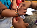 Closeup of beautiful Indian kids celebrating Raksha Bandhan by tying Rakhi to brother hand and eating sweets together