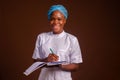 Closeup of a beautiful nurse smiling and taking notes on a brown background Royalty Free Stock Photo