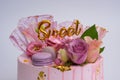 Closeup of a beautiful pink color birthday cake decorated with macarons and flowers Royalty Free Stock Photo