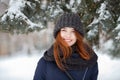 Closeup beautiful winter portrait of young adorable smiling redhead woman in cute knitted hat winter snowy park Royalty Free Stock Photo