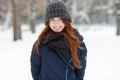 Closeup beautiful winter portrait of young adorable smiling redhead woman in cute knitted hat winter snowy park Royalty Free Stock Photo