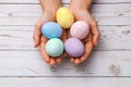 Closeup beautiful woman hands holding hand-painted easter eggs in tender pastel colors over wooden table. easter concept Royalty Free Stock Photo