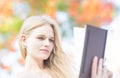 Closeup of beautiful woman reading outdoors. colorful trees Royalty Free Stock Photo