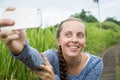 Closeup of beautiful woman taking a selfie on smart phone outdoors in summer. Young woman photographing herself smiling.