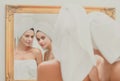 Closeup beautiful woman look in mirror after shower. Young pretty girls friends wrapped in towel smoothing perfecting