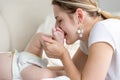 Closeup of beautiful young mother kissing baby foot lying on bed Royalty Free Stock Photo