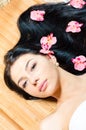 Closeup on beautiful young woman with perfect skin, blue eyes, luxury jewelry earring and orchid flowers looking at camera