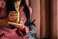 Closeup beauty female hands in pajamas holding golden metallic mug with hot beverage relaxing on bed Royalty Free Stock Photo