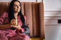 Closeup beauty female hands in pajamas holding golden metallic mug with hot beverage relaxing on bed Royalty Free Stock Photo