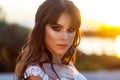 Closeup beauty portrait of beautiful calm brunette woman with makeup and hairstyle wearing white wedding dress on blurred sunset Royalty Free Stock Photo