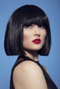 Closeup beauty portrait of a brunette woman in black wig with make up, red lips, over blue background. Royalty Free Stock Photo