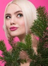 Closeup beauty portrait of young beautiful woman peeking out from behind pine branches