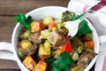 Closeup beef meat stewed with vegetables in ceramic pot with a piece on a fork on wooden background Royalty Free Stock Photo