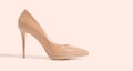 Closeup beige women patent leather shoe isolated on pink background. Stilettos shoe type. Summer fashion and shopping concept. Royalty Free Stock Photo