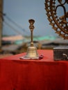 Of a bell on a table wrap with red cloth and Brass made statue of Lord Natraj with water droplets.