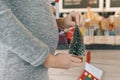 Closeup belly of pregnant woman with little christmas tree