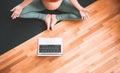 Closeup belly of pregnant woman practicing yoga online with laptop