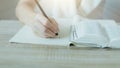 Closeup of bible and woman hand holding a pencil and write something Royalty Free Stock Photo