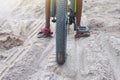 Closeup of bicycle wheels that children ride on sand.