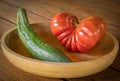 Big red heart-shaped tomato and cucumber in a wooden bowl Royalty Free Stock Photo