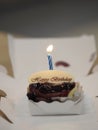 Birthday candle lit on the cake Blueberry Cheese Pie  with Whipped Cream in white paper box Royalty Free Stock Photo