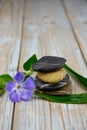 Closeup of black balancing rocks with a purple flower on a wooden surface Royalty Free Stock Photo