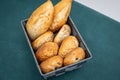 Closeup of a black basket full of fresh bread on a green tablecloth Royalty Free Stock Photo
