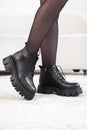 Closeup black elegant shoes on women& x27;s legs. Leather winter boots, stylish lady footwear concept