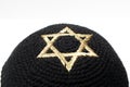 Closeup of a black jewish kippah with a golden david star.