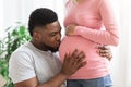 Closeup of black man kissing his pregnant wife belly Royalty Free Stock Photo