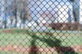 Closeup of black metal netting wire mesh fence against green field meadow. Texture pattern surface background of chain link wire- Royalty Free Stock Photo