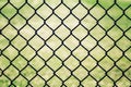 Closeup of black metal netting wire mesh fence against green field meadow. Texture pattern surface background Royalty Free Stock Photo