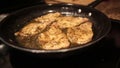 Pan / Skillet with cooking slices of seasoned pork is shaken above a stove